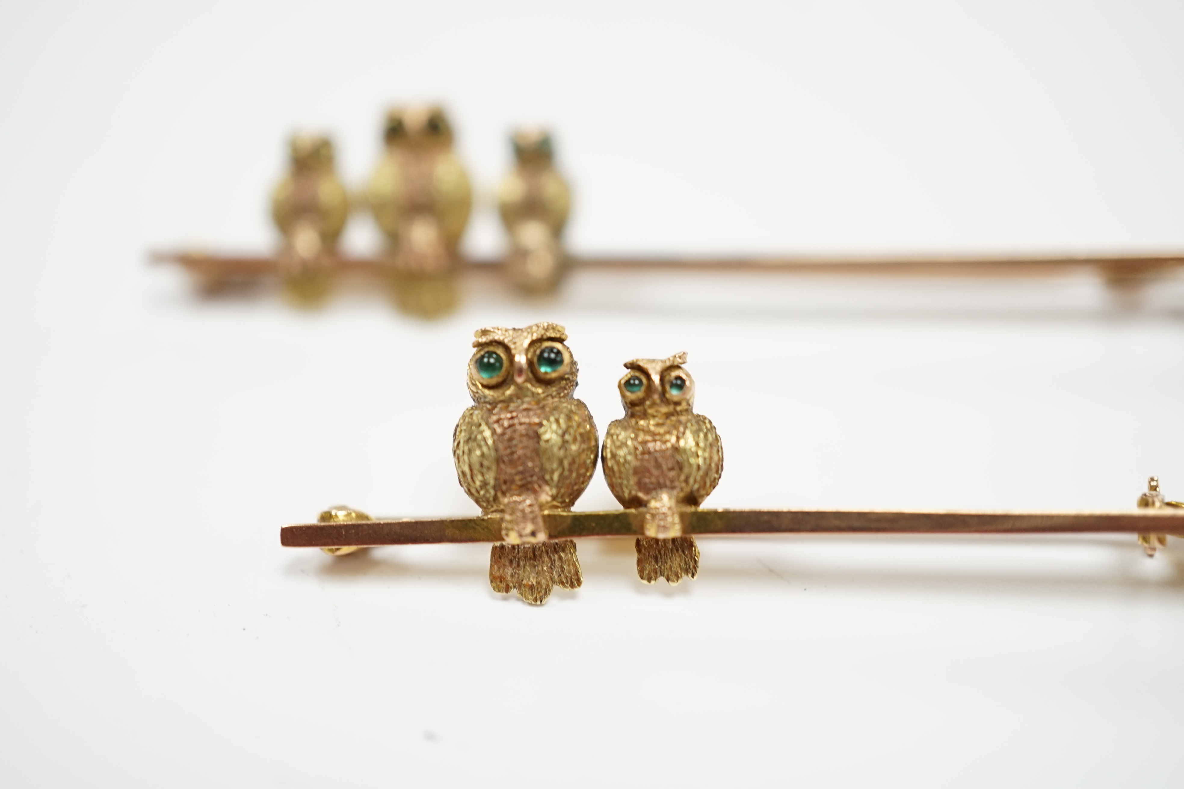 Two early 20th century 9ct owl bar brooches, with cabochon set eyes, largest 63mm, gross weight 6.9 grams.